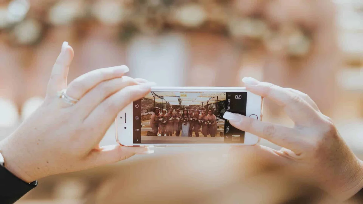 Hands holding a smartphone taking a picture of bridesmaids.