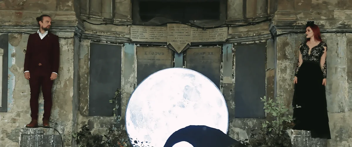 Bride and groom standing on either side of a moon backdrop against the old chapel walls at the Asylum Chapel, London
